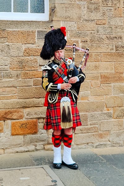 Dudelsackspieler beim Spaziergang durch Edinburgh mit Kindern